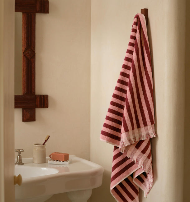 Bathroom with a striped towel hanging on a wooden towel rack next to a sink.