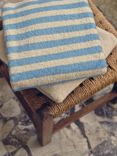 Striped towel on a wicker chair with a patterned floor background