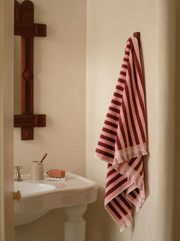 Bathroom with a striped towel hanging on a wooden towel rack next to a sink.