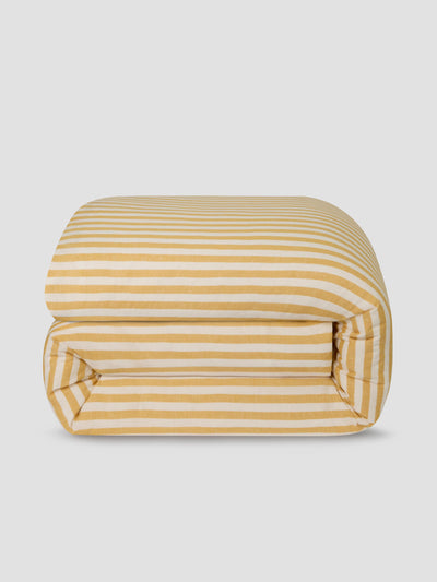 Folded yellow and white striped duvet on a light gray background