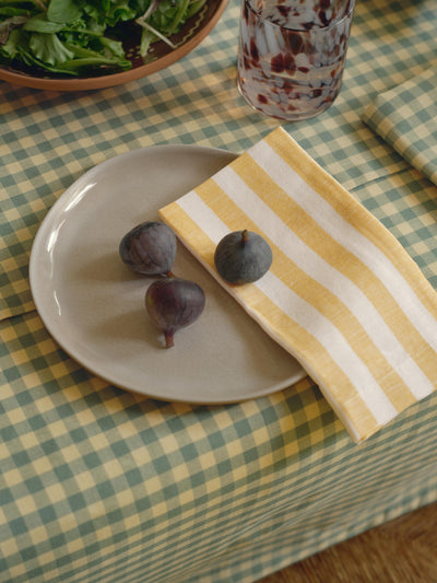 Plate with figs on a checkered tablecloth with a striped napkin.