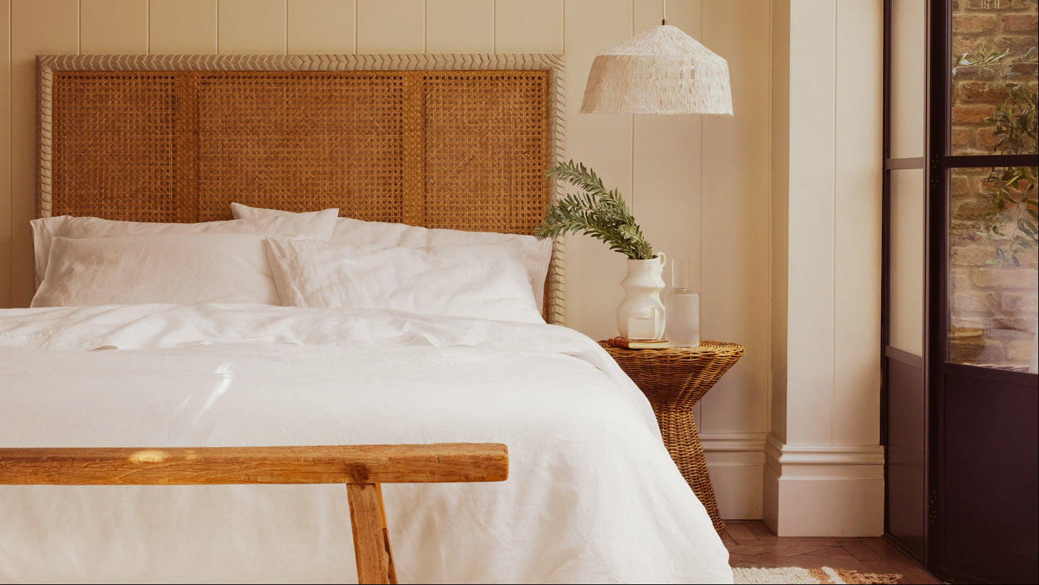 White linen bedding with rattan headboard